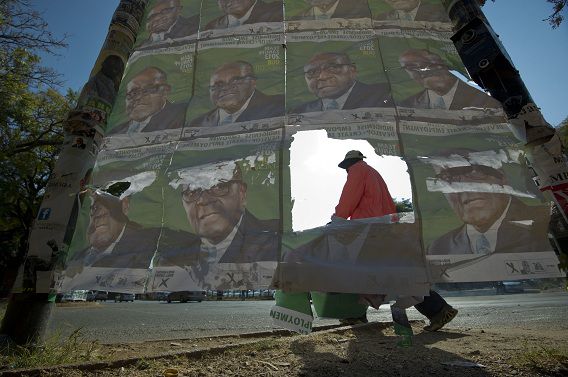 Een Zimbabwaan op weg naar zijn werk loopt langs posters van president Robert Mugabe vandaag in Harare. Zimbabwe maakt zich klaar voor de verkiezingen morgen.