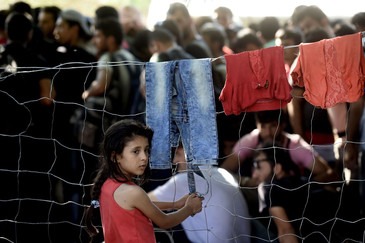 Een jong meisje staat bij een hek in een registratiekamp in Presovo in Servië. Daar kwamen vandaag vluchtelingen en migranten uit Syrië aan.