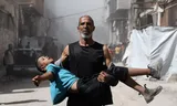 Een Palestijnse man draagt een kind dat gewond is geraakt na een Israëlische luchtaanval op Gaza-stad op 7 september 2025. Foto Khamis Al-Rifi/ Reuters