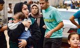 Een gewonde vrouw draagt zondag een baby na een Israëlisch bombardement in Rafah, in het zuiden van de Gazastrook.