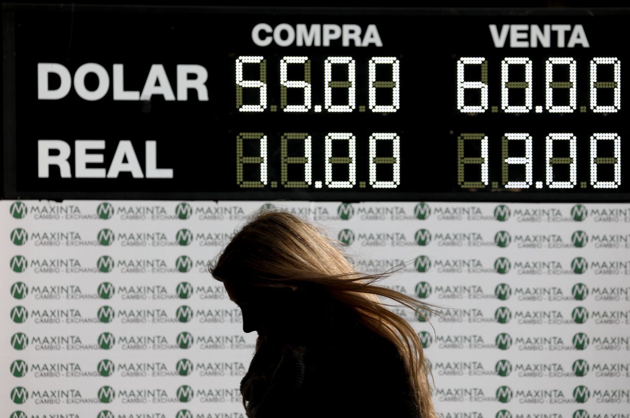 Een vrouw loopt langs een scherm dat de wisselkoersen toont in Buenos Aires, Argentinië.