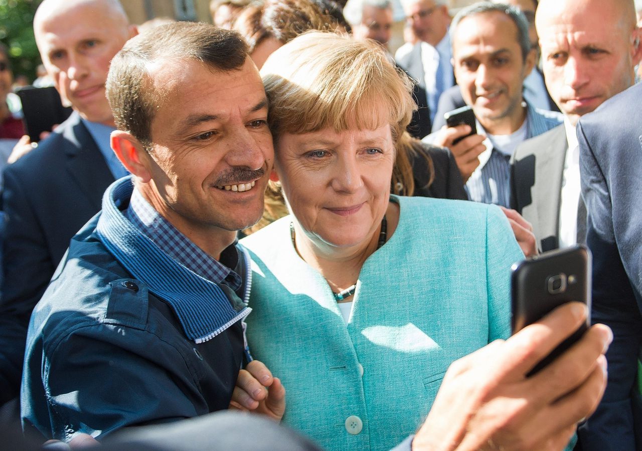 Merkel gaat op de foto met een vluchteling tijdens een bezoek aan een vluchtelingenkamp in Berlijn. Foto Bernd von Jutrczenka/EPA