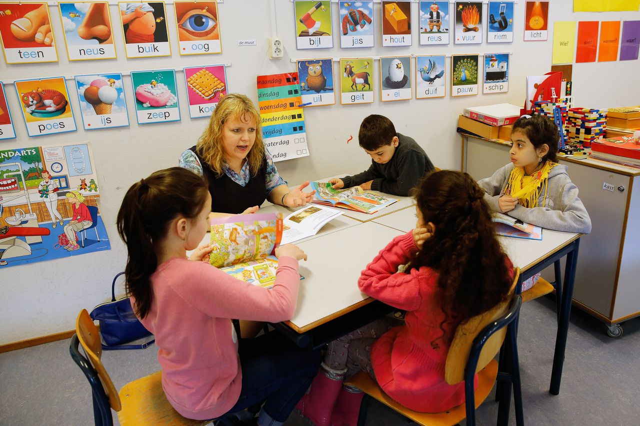 Kinderen leren Nederlands in een azc. Volgens de jongste inzichten is les in de eigen taal ook belangrijk.