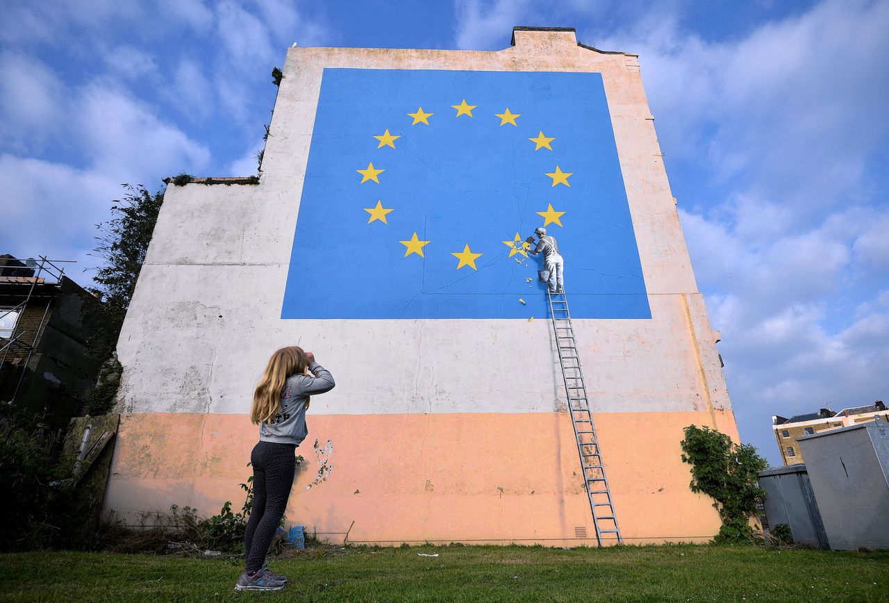Een jonge vrouw maakt een foto van een kunstwerk van Banksy in het Britse Dover