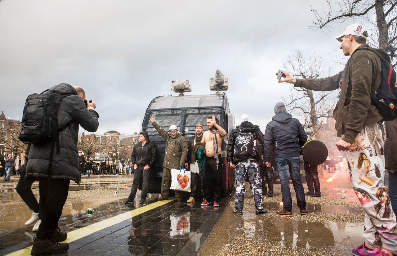 Betogers poseren voor het waterkanon van de politie bij de verboden demonstratie tegen het kabinetsbeleid op het Museumplein.