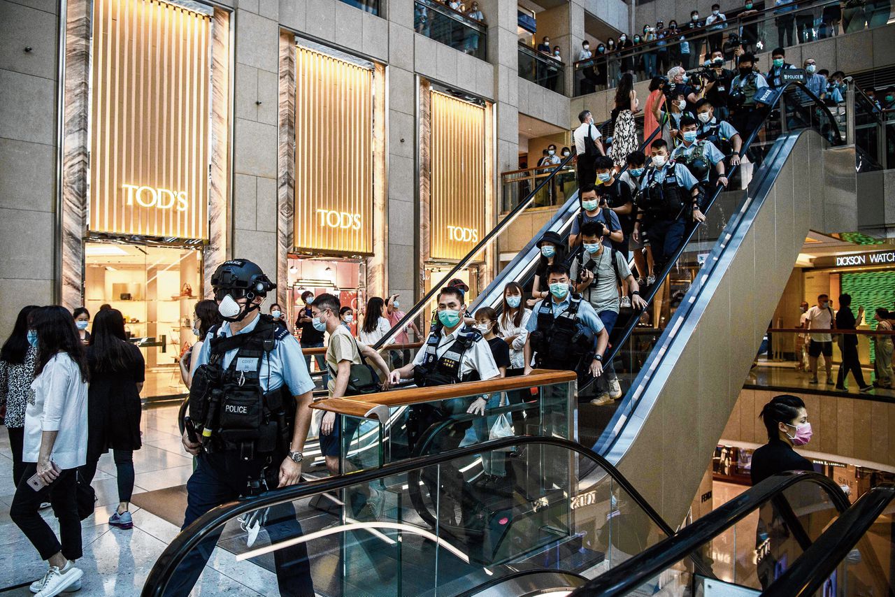 Politieagenten lopen op de demonstrerende activisten in het winkelcentrum af.