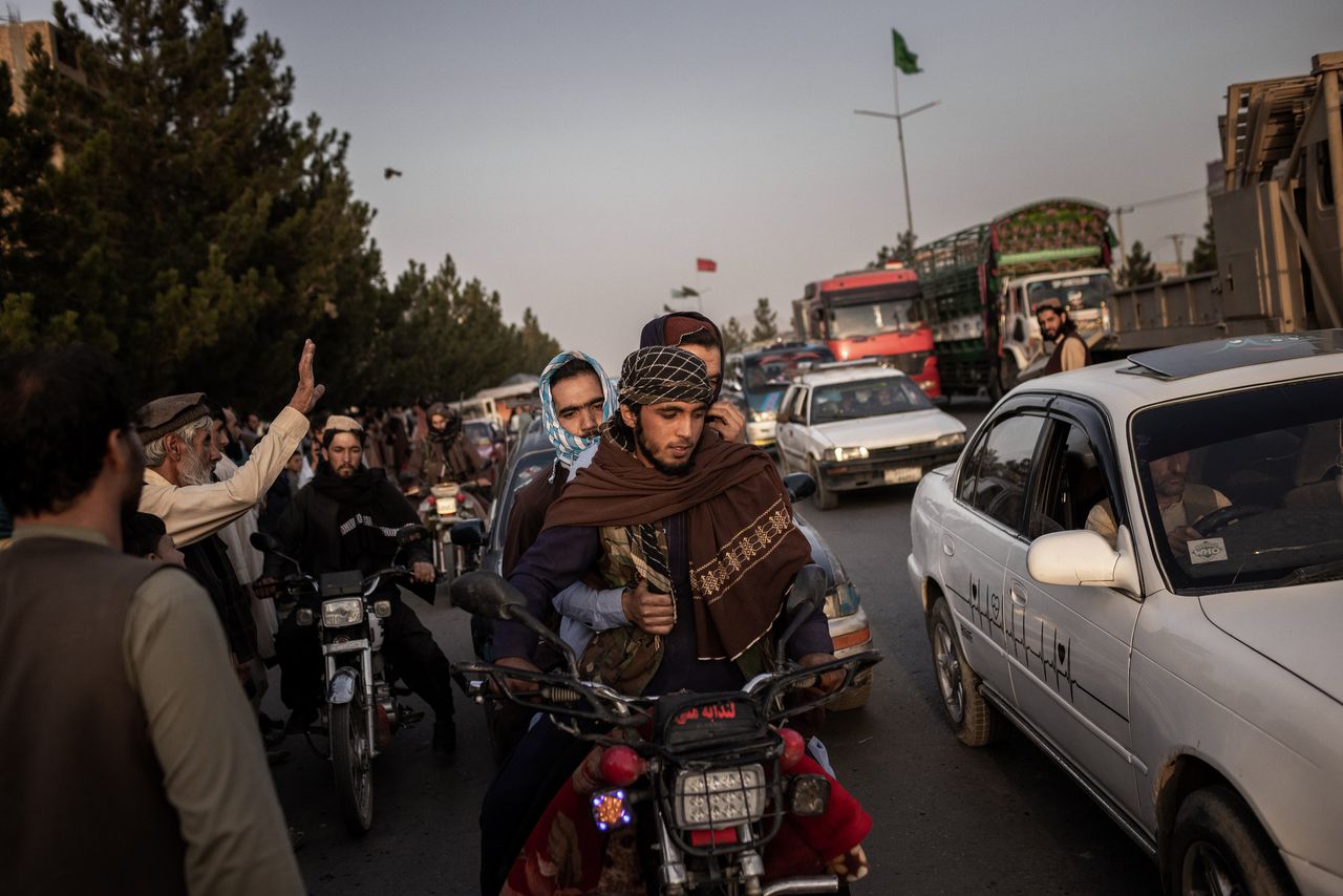 Omstanders groeten de Taliban strijders die Kabul binnen komen rijden.