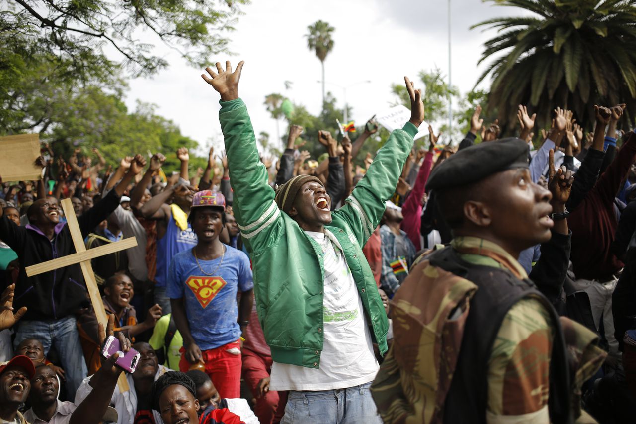 Demonstranten kijken naar een overvliegende helikopter. De Zimbabweanen, die protesteerden tegen Mugabe, werden tegengehouden door de strijdkrachten, op naar de de ambtswoning van de afgezette president.