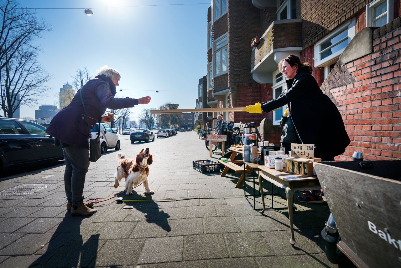 Bewoners aan de Amsteldijk in Amsterdam die koffie verkopen geven de spullen aan via een plank van 1,5 meter.