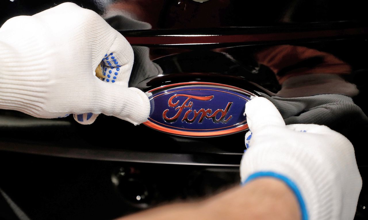 Een medewerker plakt het Ford-logo op een auto in een fabriek in Keulen, Duitsland.