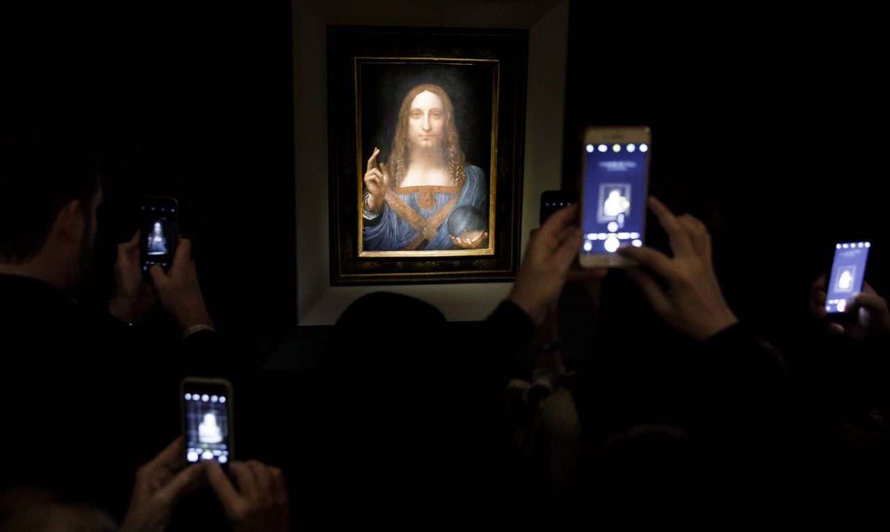 Bezoekers fotograferen het Da Vinci-schilderij tijdens een kijkdag voorafgaand aan de veiling.