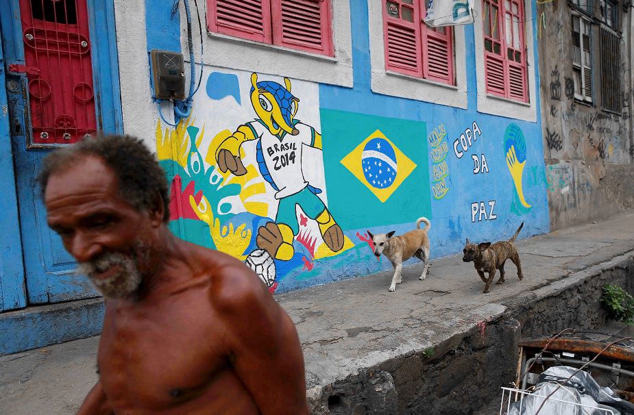 Een man loopt langs een graffititekening van de mascotte van het WK in een wijk in Rio de Janeiro, een van de speelsteden.