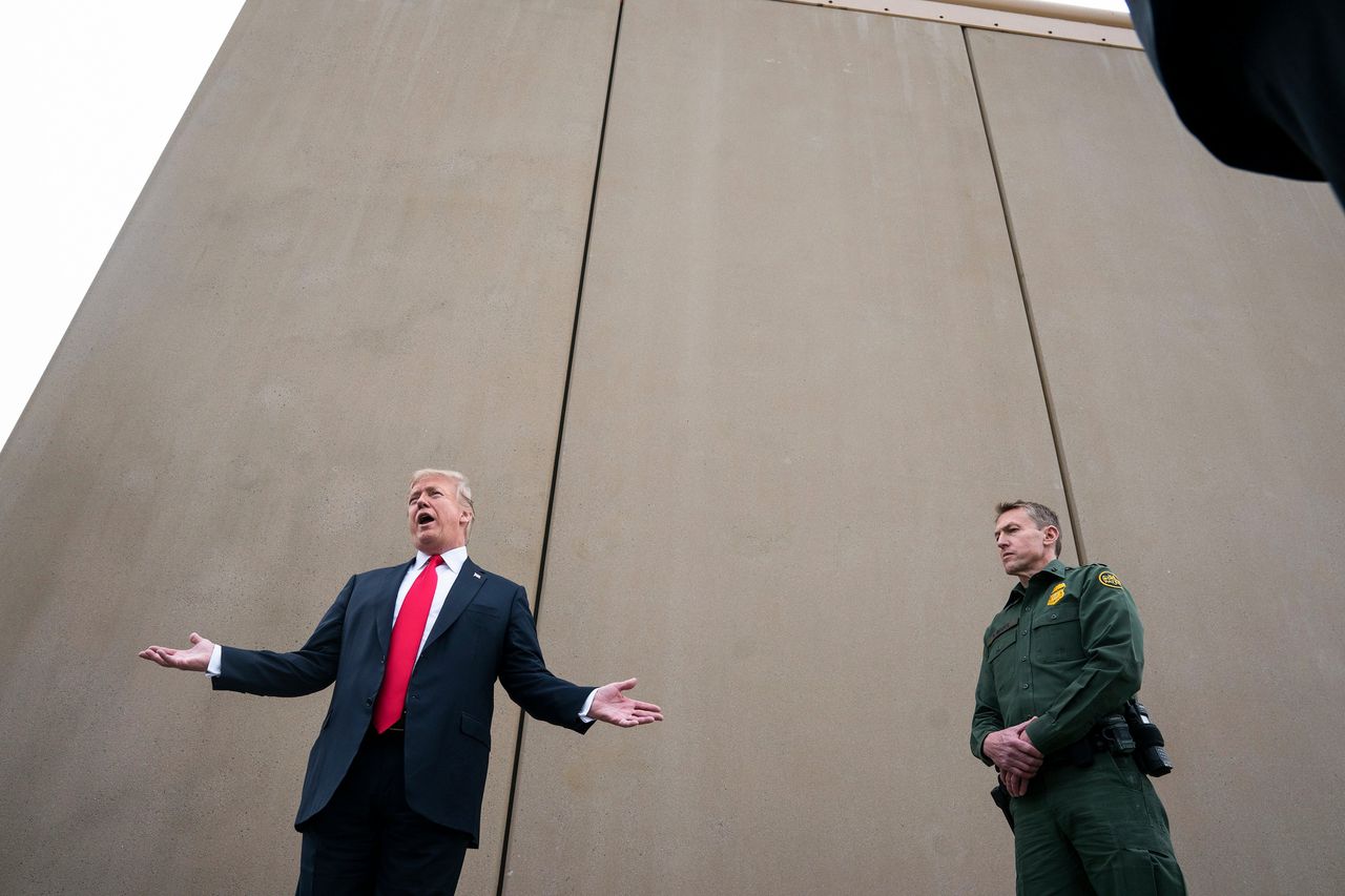 Veertien maanden na zijn aantreden reist Trump af naar de zuidgrens. De maanden daarvoor hebben aannemers aan de rand van San Diego in Californië acht prototypes van de muur neergezet.