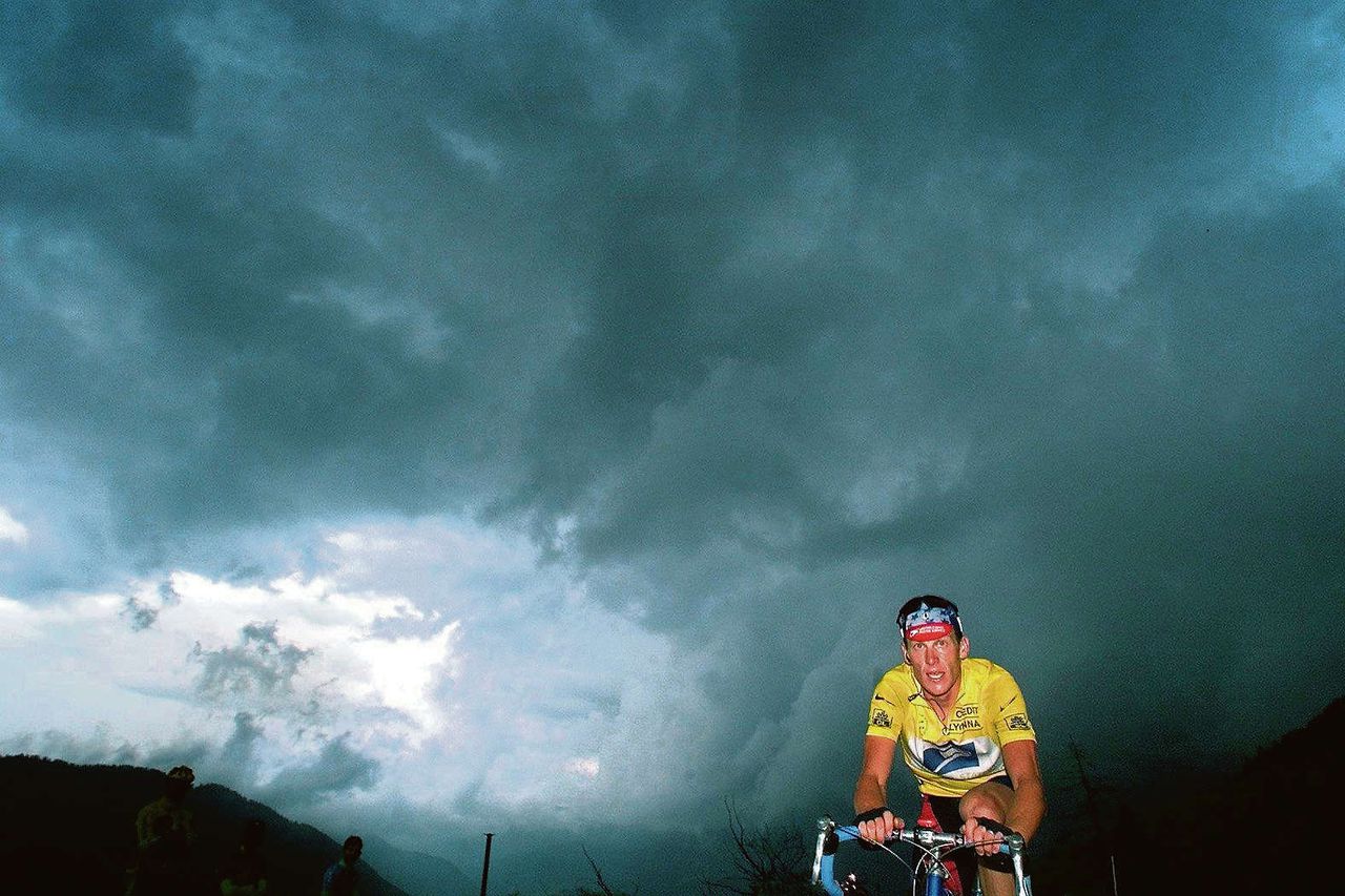 Lance Armstrong tijdens de Tour van 1999. Oudenaarden: „Er was een enorme onweerswolk. Ik had bijna geen licht meer in de camera. Toen heb ik mijn flitser gebruikt. Dat dreigende vind ik mooi, als eenling kwam hij boven. Later heeft deze foto heel veel lading gekregen: donkere wolken hingen toen al boven Armstrong.”