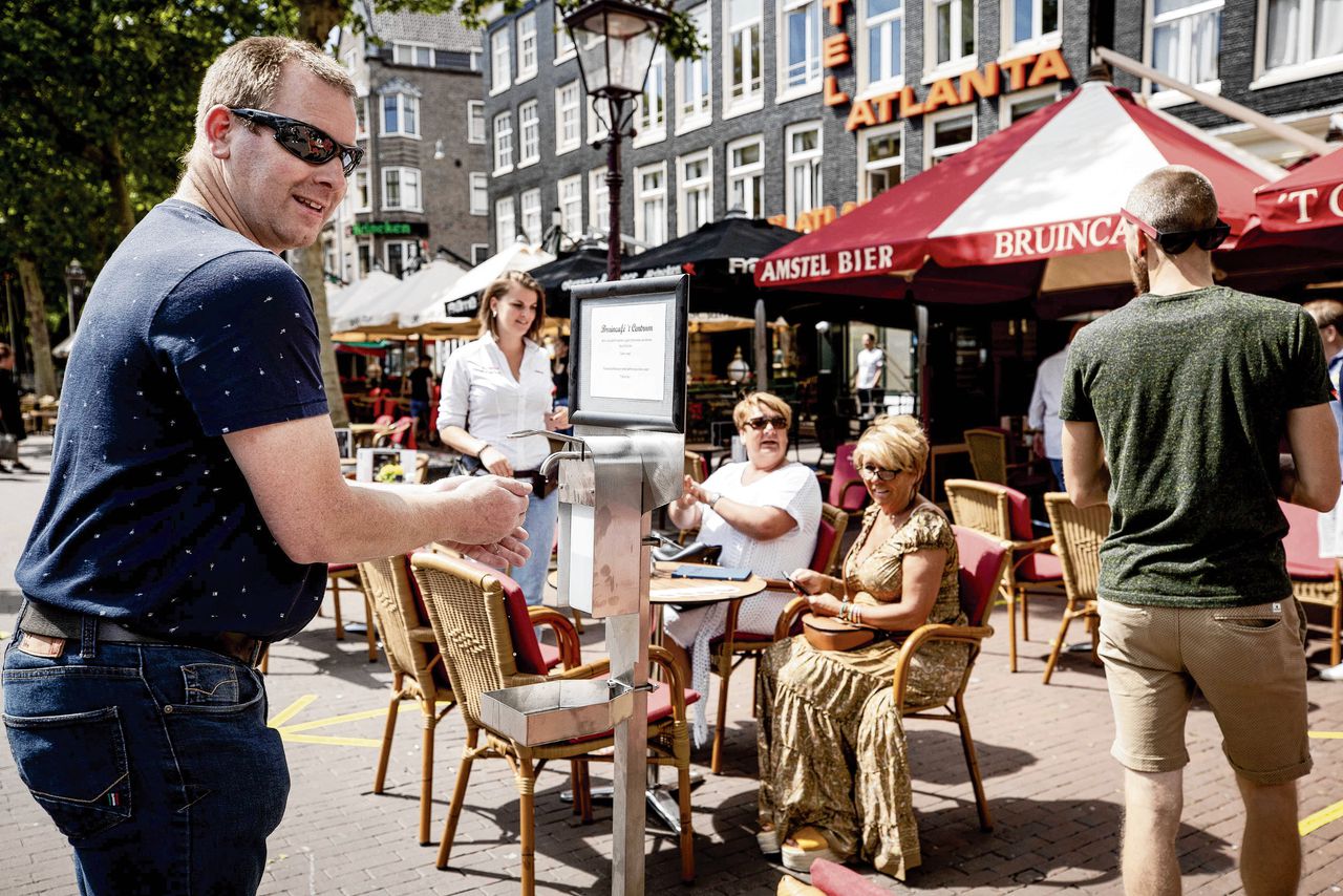 Een gast desinfecteert zijn handen op een terras aan het Rembrandtplein.