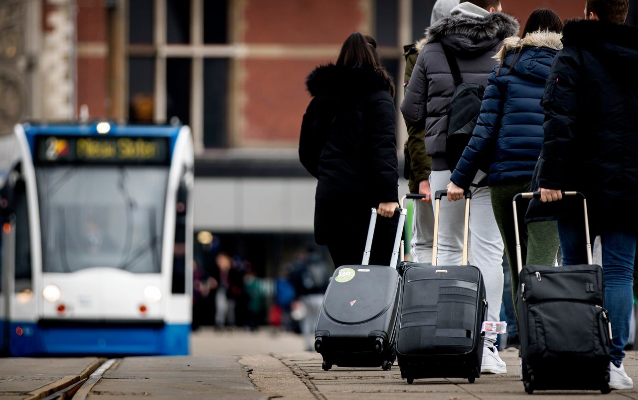 Toeristen met rolkoffers in het centrum van Amsterdam. Het geratel van rolkoffers is een van de symptomen van toenemend toerisme in de hoofdstad.