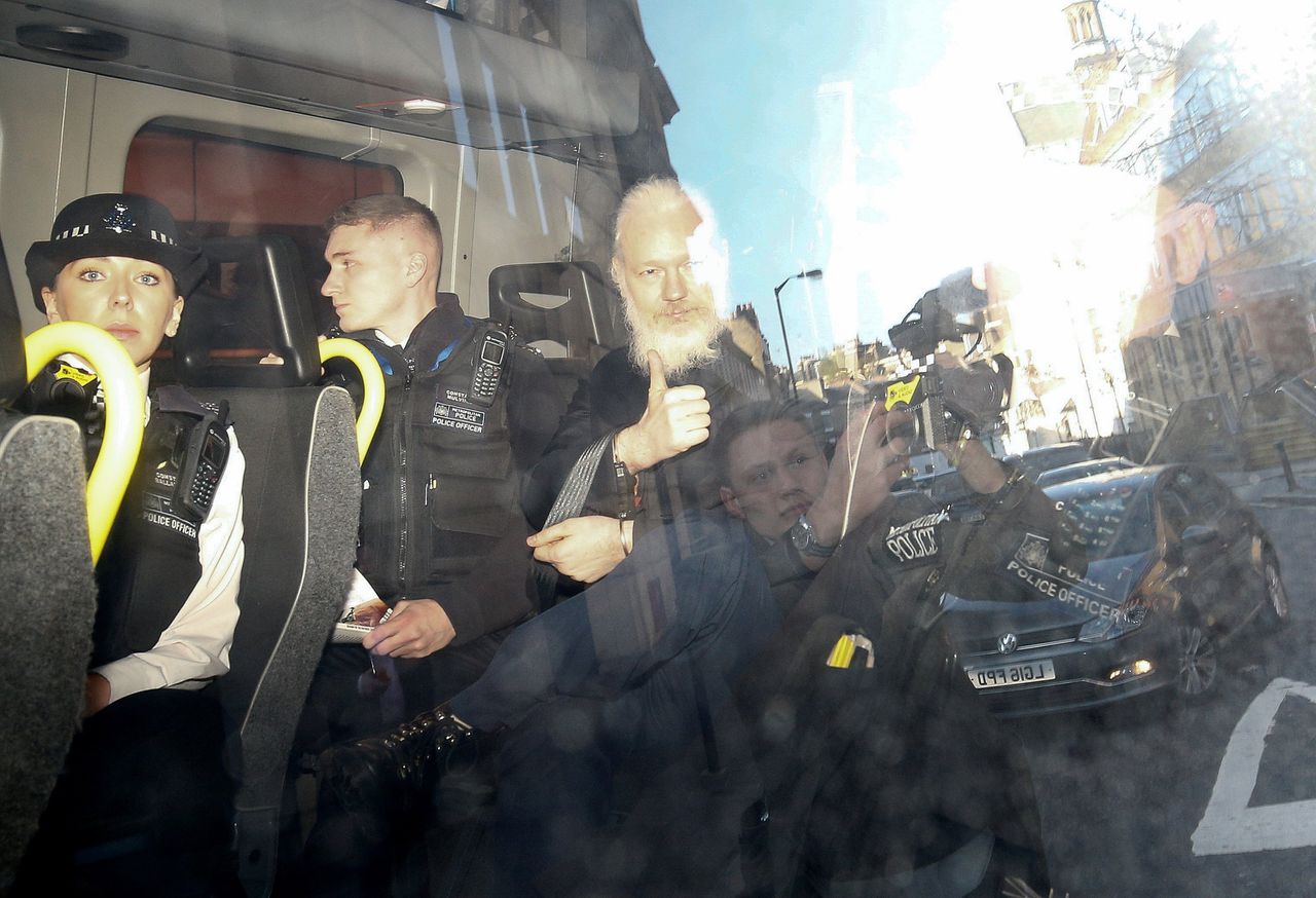 Julian Assange donderdag bij het verlaten van de Londense rechtbank in een politiebusje.