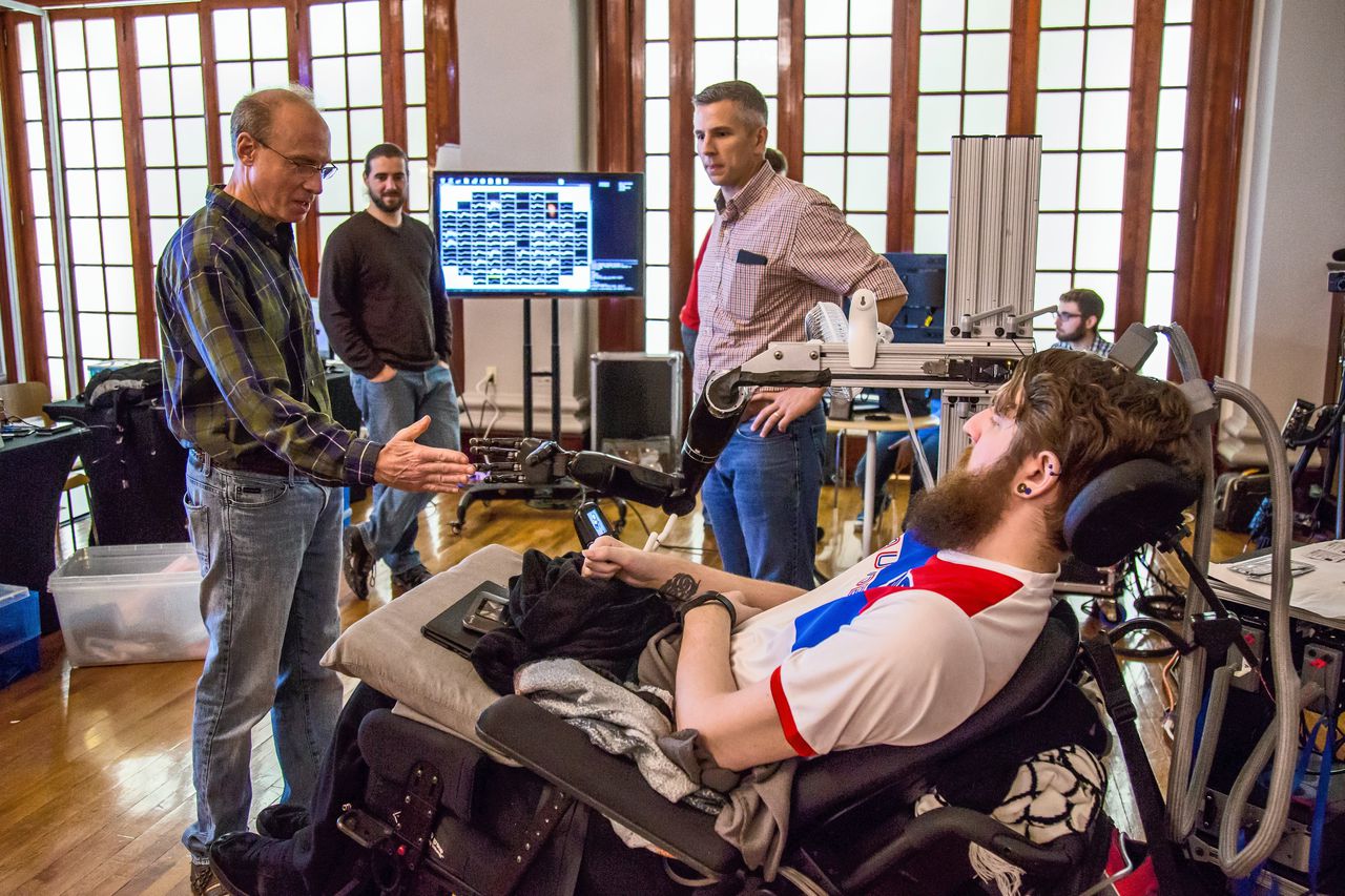 Nathan Copland, met hersenchip uitgerust, geeft Andrew Schwartz een hand. Schwartz, hoogleraar aan Pittsburgh Medical School, ontwikkelde de hersenelektrode waarmee Copland zijn bionische arm bestuurt.