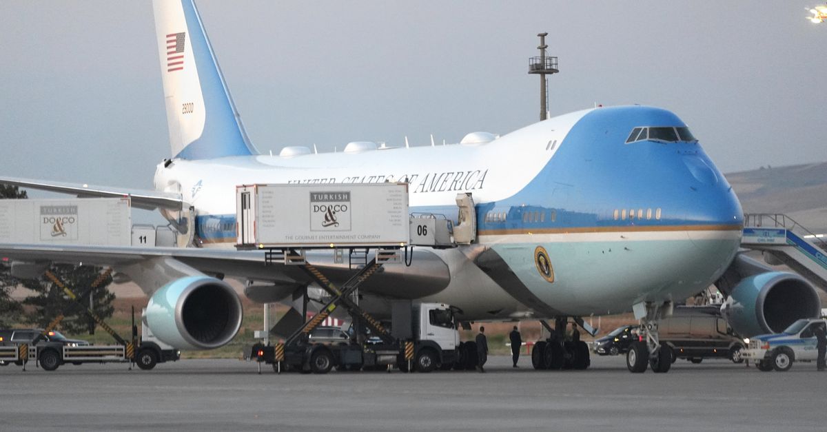 Cateringwagens staan ​​geparkeerd bij Air Force One op het platform terwijl de colonne met de Amerikaanse president Donald