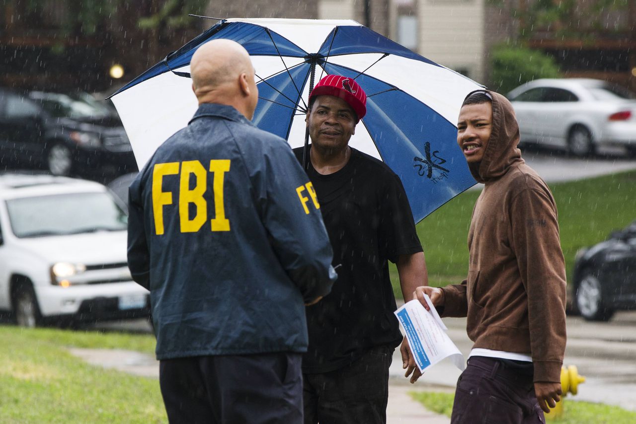 Een FBI-agent in gesprek met inwoners van de wijk waar Brown werd doodgeschoten.