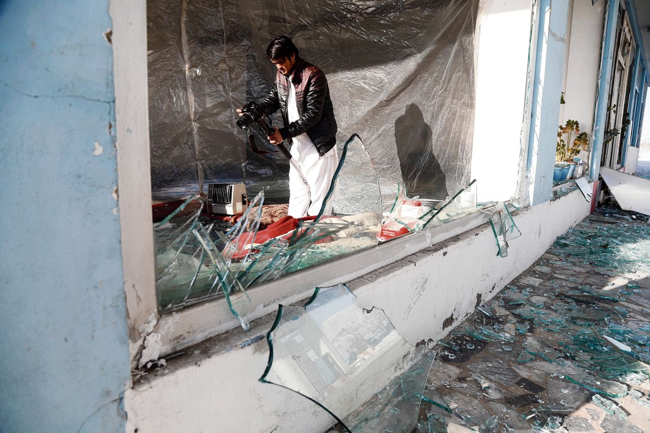 Een Afghaanse persfotograaf legt de schade vast van de aanslag van maandag op een gebouw van de inlichtingendienst.