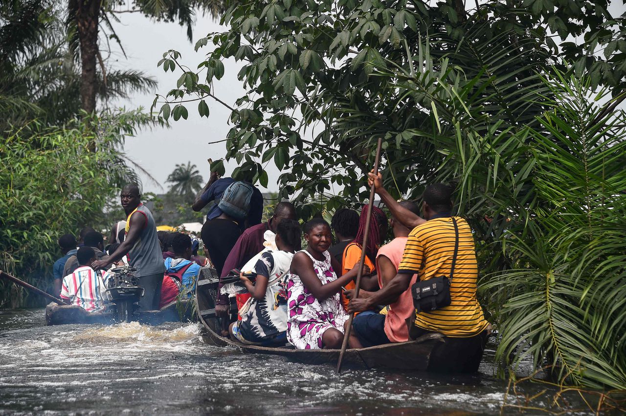 Mensen bewegen zich vrijdag voort in bootjes in zuidelijk Nigeria, waar een belangrijke snelweg onbegaanbaar is wegens zware overstromingen.