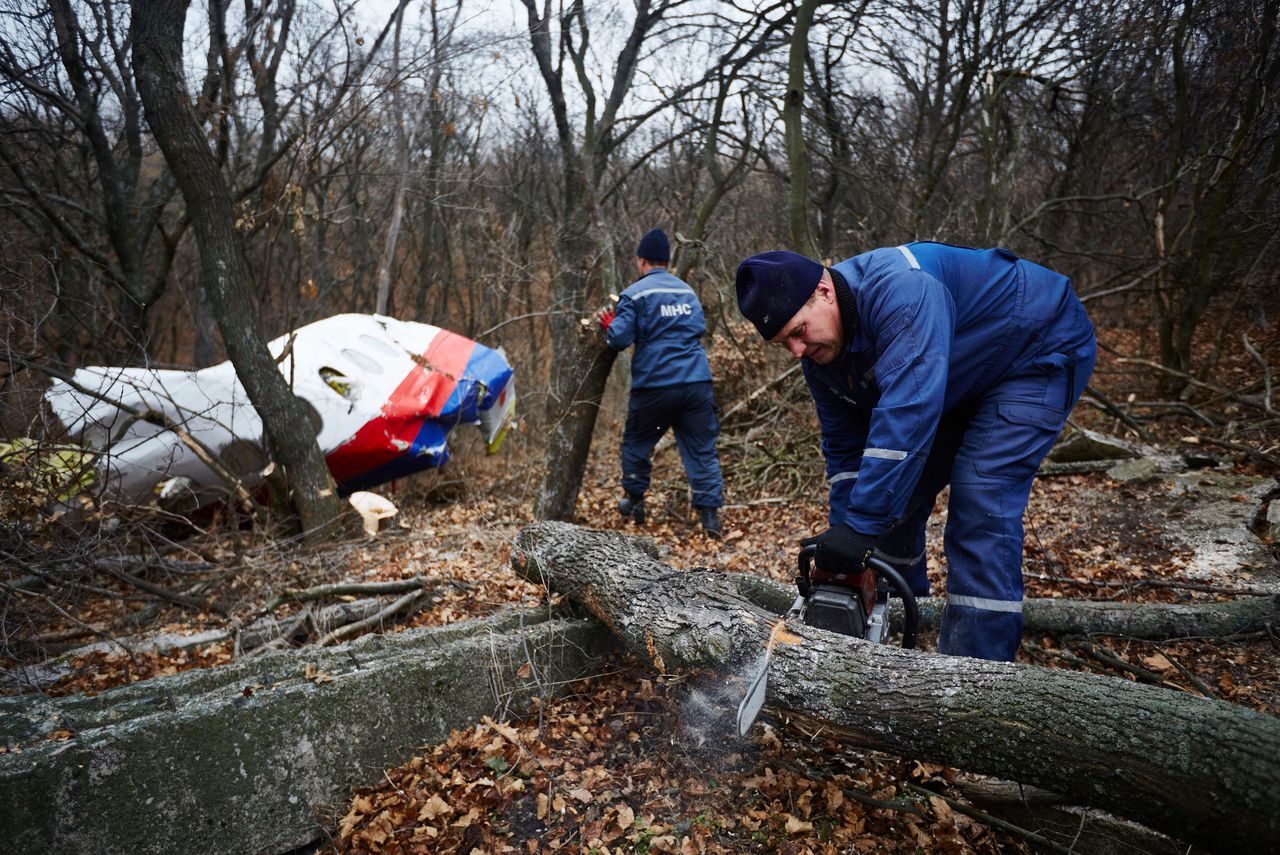 Oekraïense reddingswerkers zagen bomen weg bij een groot vliegtuigonderdeel van de neergestorte MH17.