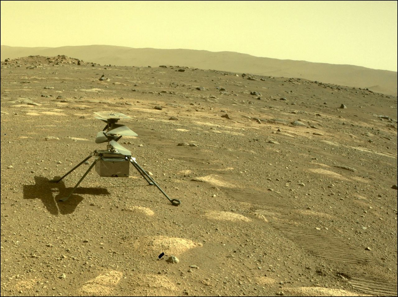 Het helikoptertje ‘Ingenuity’ op het Marsoppervlak, gezien door de achteruitkijkcamera van Marsrover Perseverance.