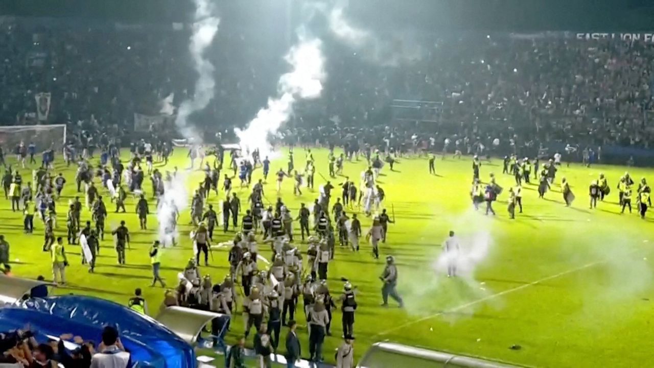 Televisiebeeld van het moment dat voetbalfans het veld bestormen.