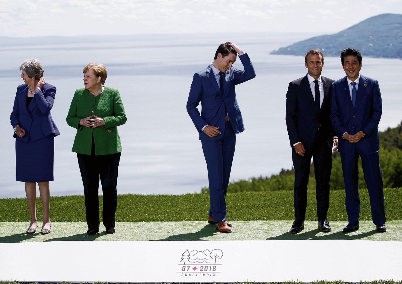 De Britse premier May, de Duitse bondskanselier Merkel, de Canadese premier Trudeau, de Franse president Macron en de Japanse premier Abe wachten op Trump bij de G7 in Québec.