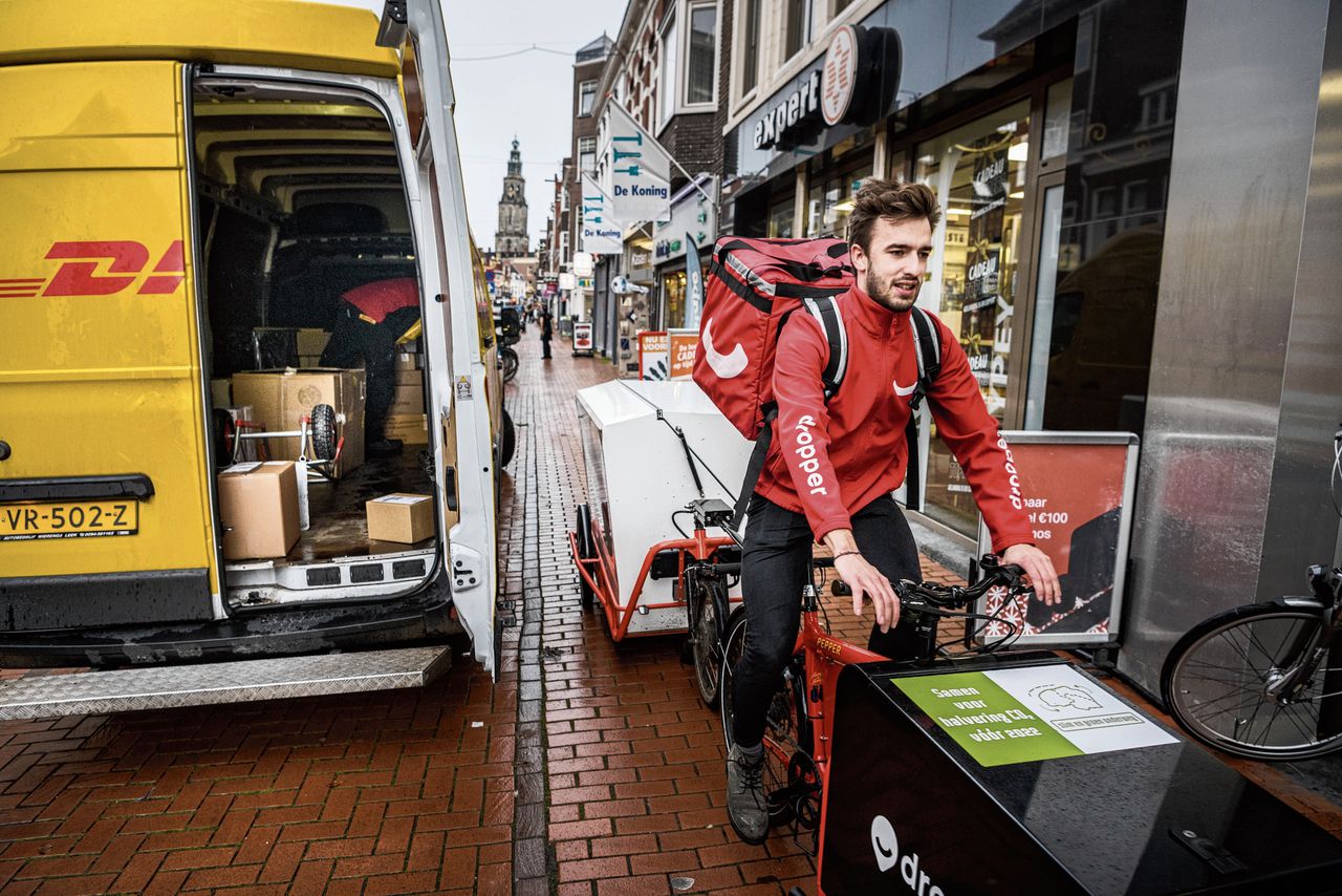 Een bezorger van Dropper fietst door de binnenstad van Groningen. De dienst bezorgt nu ook voor 45 lokale winkeliers die zijn aangesloten bij de website Warenhuis Groningen.