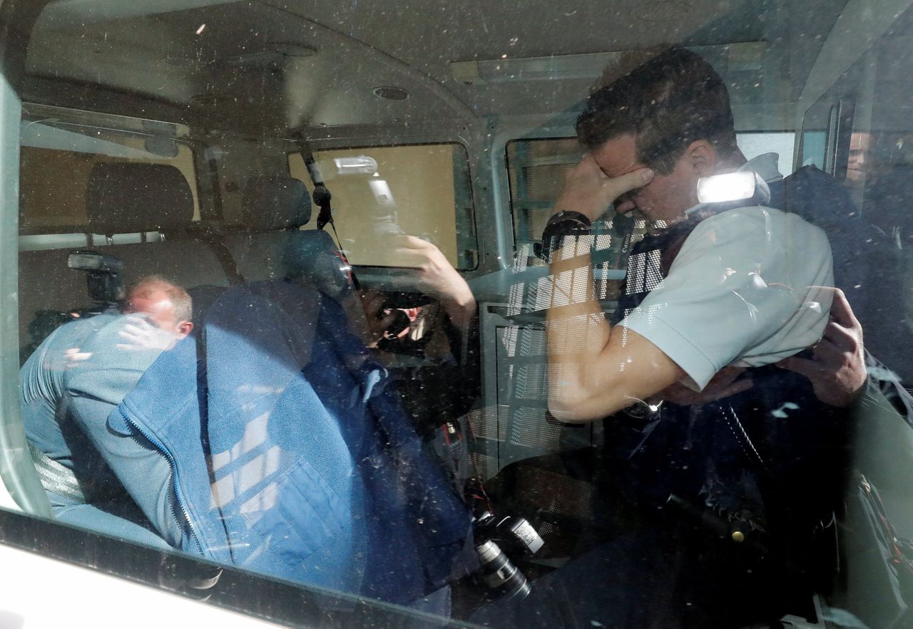 De verdachte scheidsrechter Bart Vertenten (links) verbergt zich onder een jas bij het verlaten van de rechtbank in Tongeren.