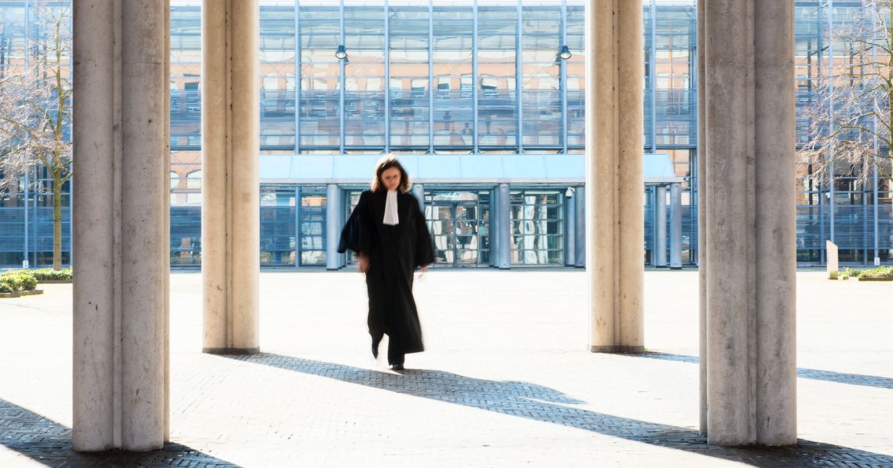 Een rechter loopt op een plein voor de rechtbank.
