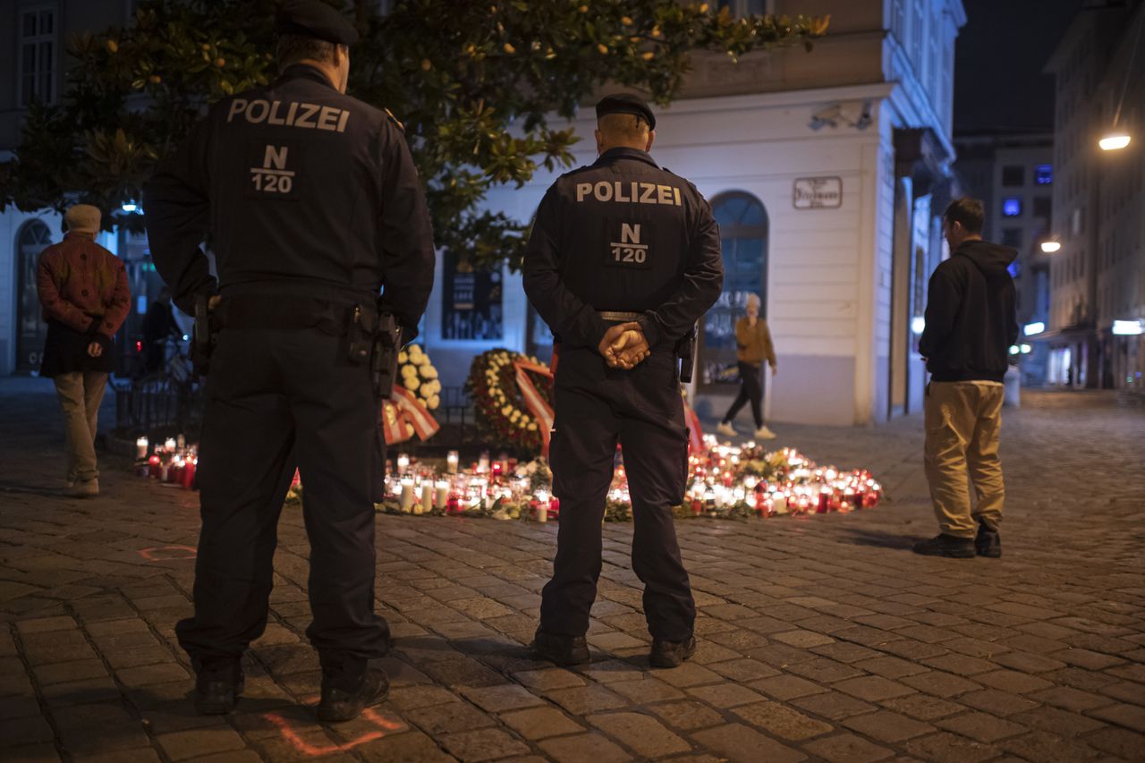 Oostenrijkse politieagenten staan stil bij een op straat ingericht gedenkteken aan slachtoffers van de aanslag in Wenen.