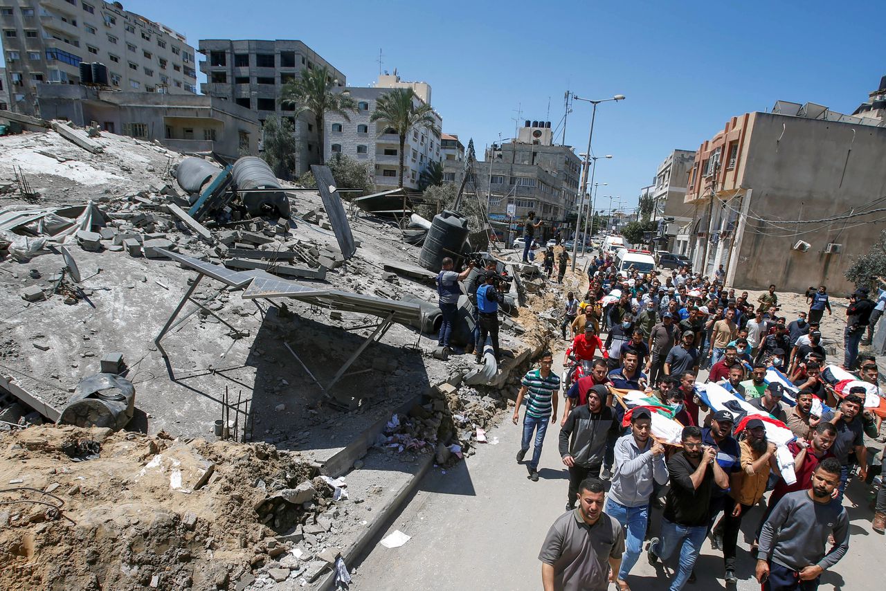 Lichamen van omgekomen Palestijnen worden vervoerd langs een verwoest gebouw.