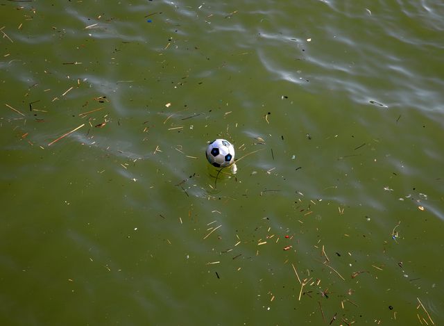 Voetballende kinderen zien dat hun bal in het water naast de kade is gevallen. 