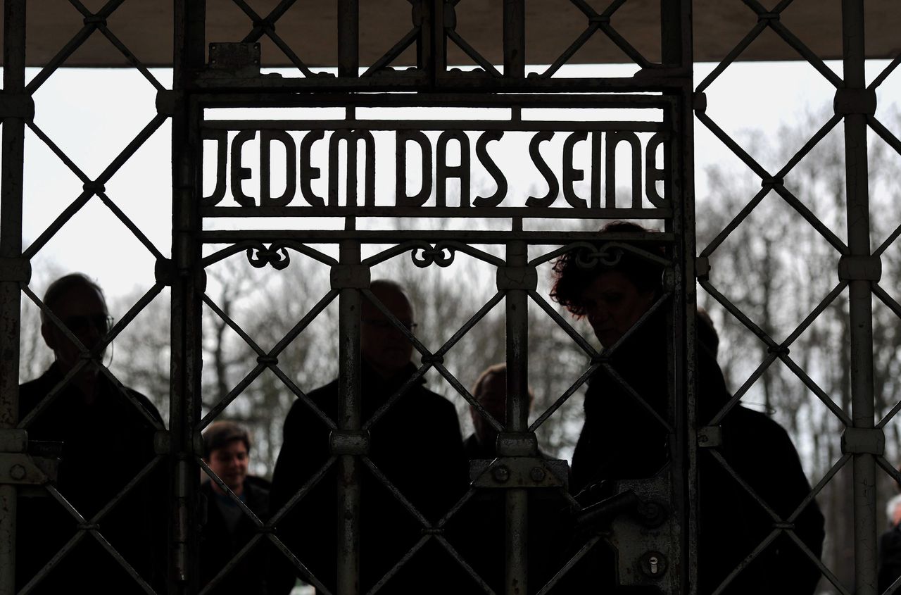 Bezoekers van het concentratiekamp Buchenwald lopen langs een van de poorten met daarop 'Jedem das Seine' (Ieder het zijne, of losser vertaald 'ieder krijgt wat hij verdient').