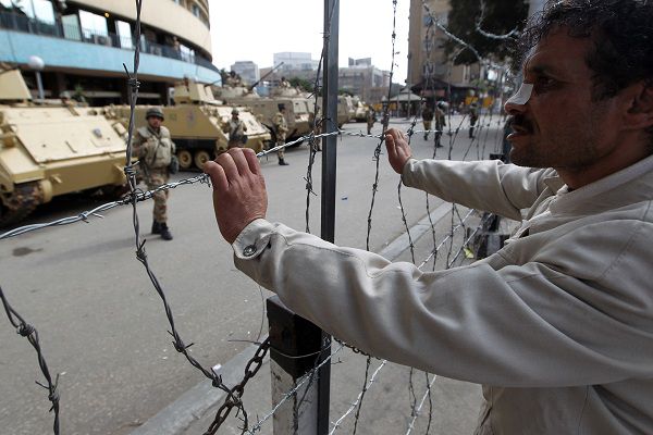 An injured Egyptian anti-government protester holds onto barbed wires outside the state television building in Cairo on February 11, 2011. Thousands of demonstrators massed at Egypt's state television building and at President Hosni Mubarak's palace in the Cairo suburbs as anti-regime protests spread across the city. AFP PHOTO/KHALED DESOUKI