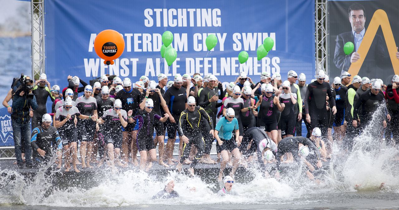 Deelnemers van de Amsterdamse City Swim springen in het water. Ze hebben geld opgehaald voor onderzoek naar de spierziekte ALS. Door de kou zijn een aantal van hen onderkoeld geraakt, waarop de organisatie een deel van het parcours heeft ingekort.