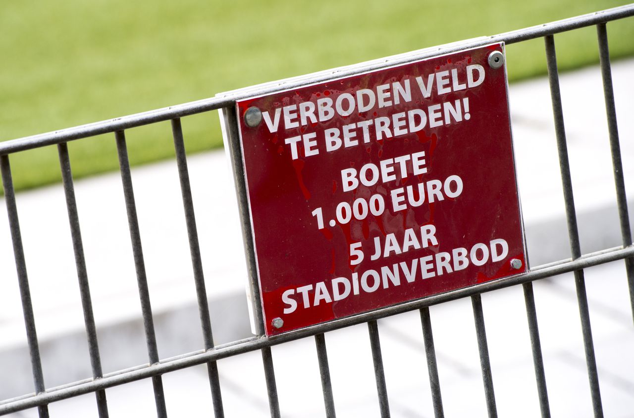 Een bordje waarschuwt voor een stadionverbod en een boete bij het betreden van het veld