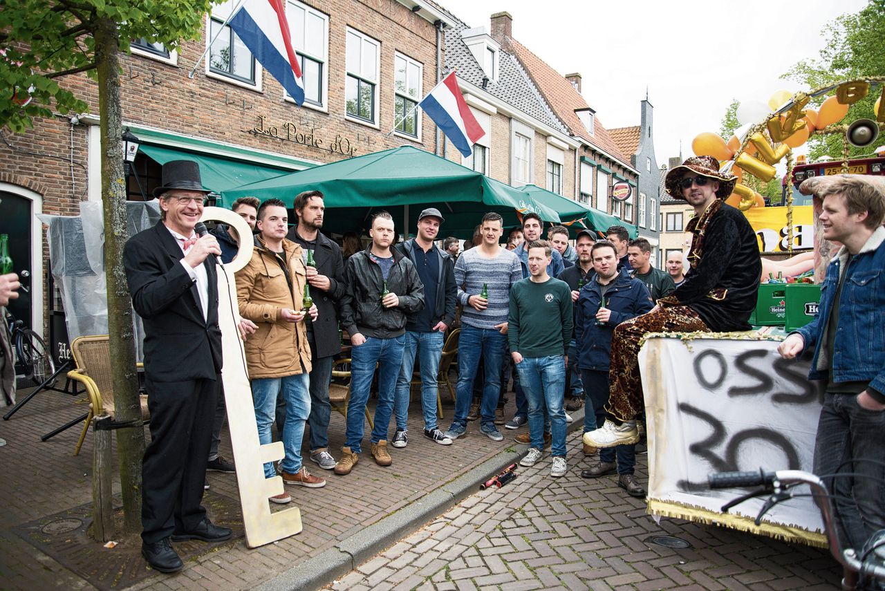 De dertigste verjaardag van Glenn van de Voorde uit IJzendijke. Van de Voorde (met zonnebril en hoed) moest op een kar en kreeg de ‘sleutel van de ossewei’ van de dorpsomroeper (links).