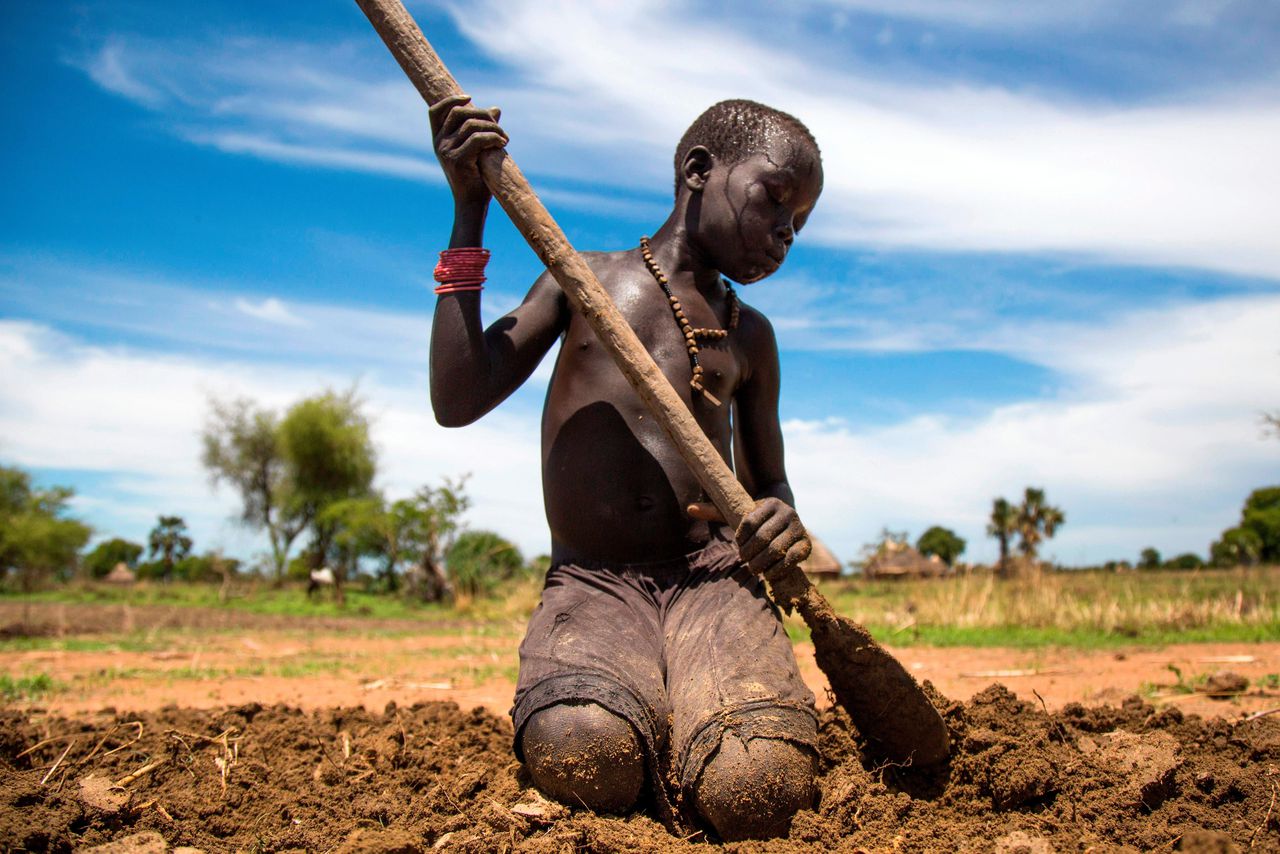 Een dertienjarige jongen is aan het werk op het land in Panthau, Zuid-Soedan.