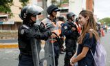 Een aanhanger van Guaidó staat glimlachend voor een agent van de oproeppolitie tijdens een protestmars zaterdag.