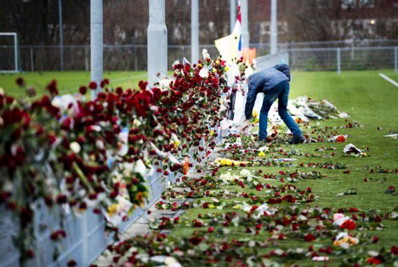 Een man rangschikt op de dag van de uitvaart van de overleden grensrechter Richard Nieuwenhuizen de bloemen bij het hek langs het veld van voetbalclub SC Buitenboys. Foto ANP / Robin Utrecht