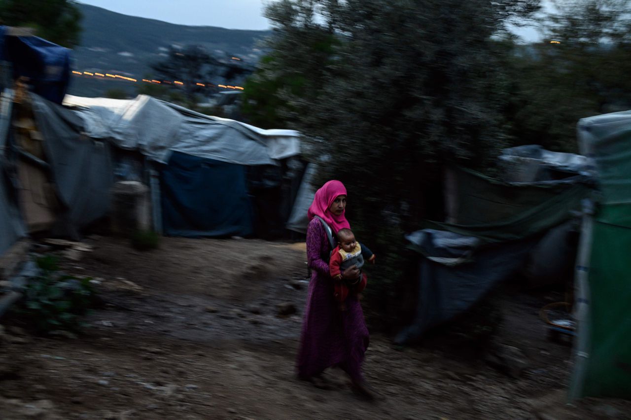 Een vrouw loopt met haar baby door een overbevolkt kamp op het Griekse eiland Samos.
