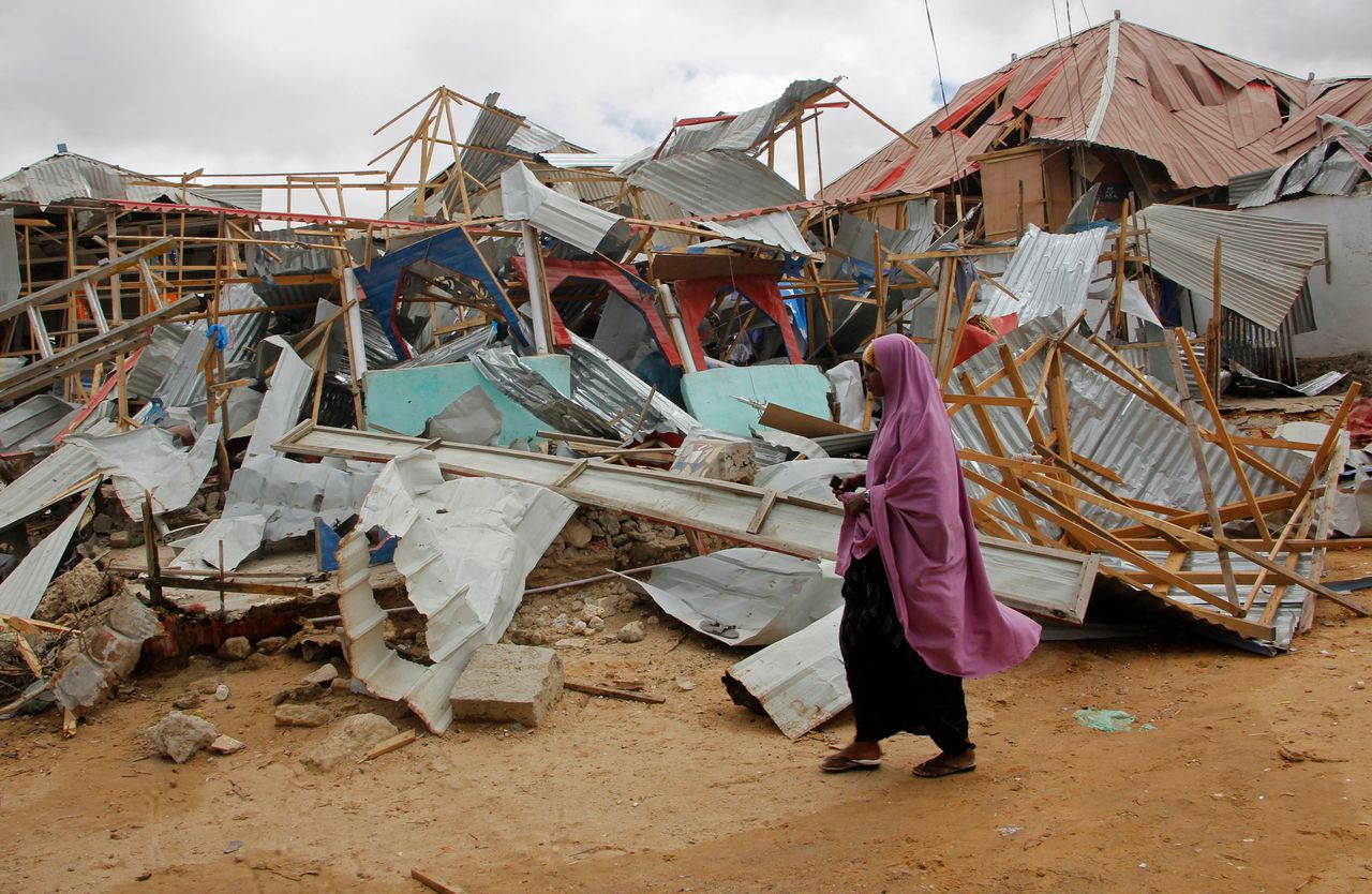 Een vrouw loopt langs een ingestort gebouw nadat een autobom is afgegaan in Mogadishu op 8 juli.