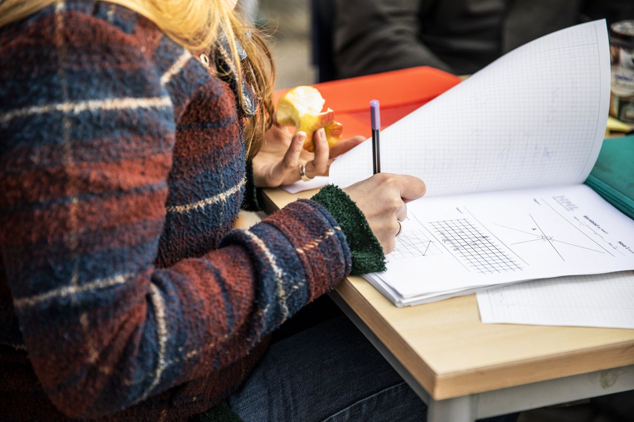 Bij een lerarenstaking in Den Haag kijken enkele leraren het huiswerk van leerlingen na.
