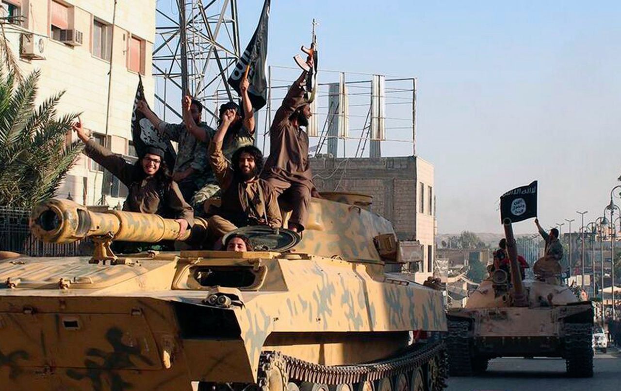 Strijders van Islamitische Staat (IS) rijden in juni 2014 door de straten van het Syrische Raqqa.