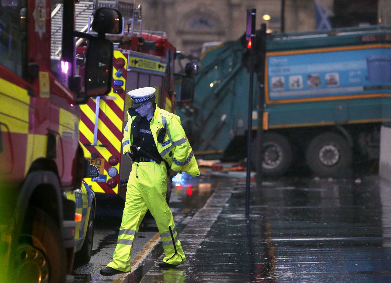Een Schotse agent is aanwezig op de plek waar de botsing plaatsvond. Op de achtergrond is de vuilniswagen zichtbaar.