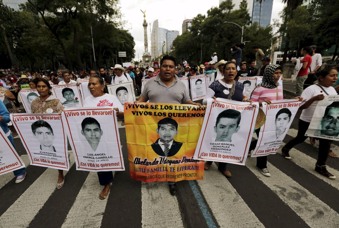 Demonstranten houden borden met foto's van vermiste Mexicaanse studenten omhoog tijdens een protestmars.